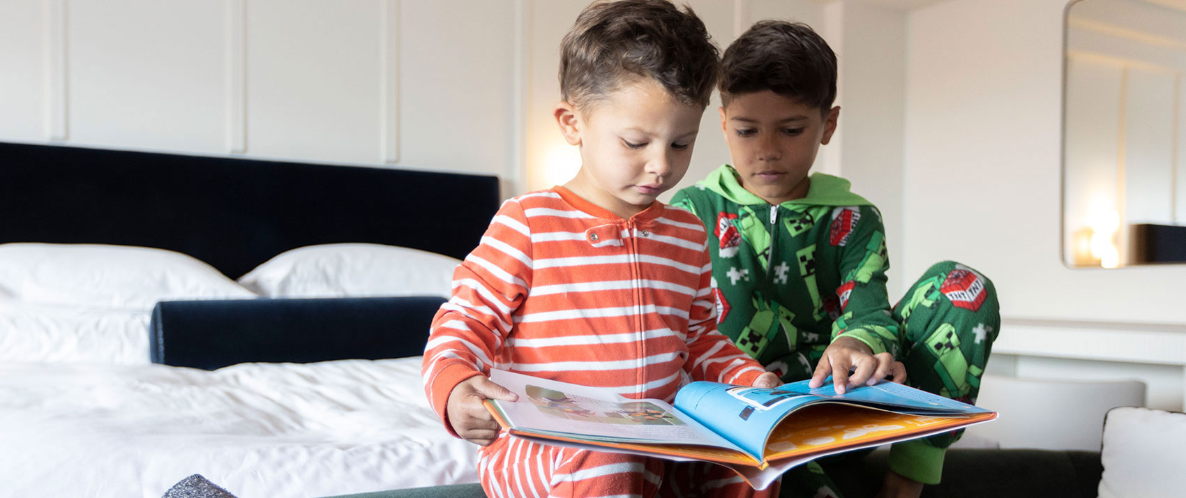 two boys reading on bed